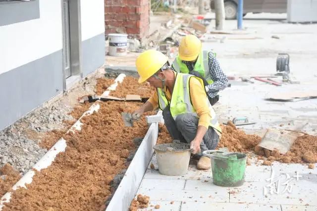 工人在修筑花槽美化村容。 图片